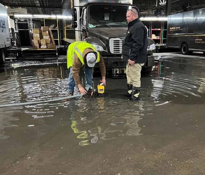 Two technicians work on a water pump standing in several inches of water