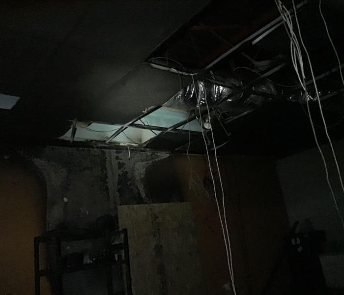 Wires hang down from ceiling, walls and ceiling are entirely black with soot